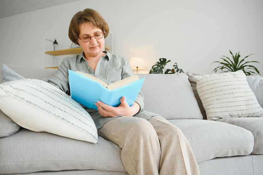 portrait relaxed senior woman sitting sofa book