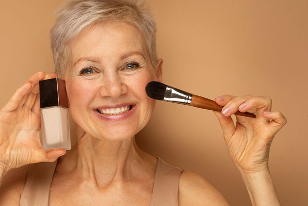 pretty elderly lady holds makeup brush foundation her hands prepares