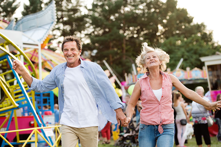 senior couple at the fun fair holding hands running senior couple at the fun fair holding hands running