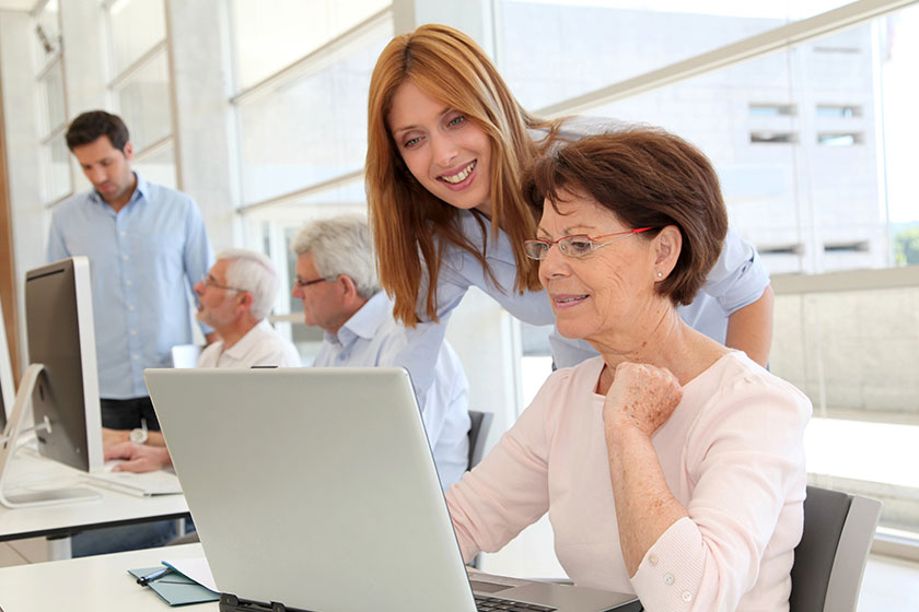 Senior woman with trainer in front of laptop computer