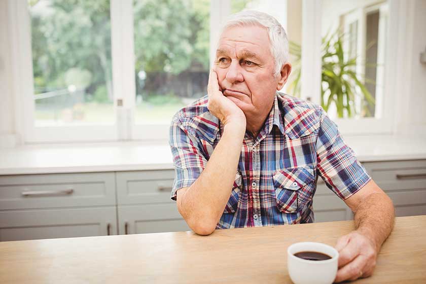 thoughtful senior man sitting at table thoughtful senior man sitting at table