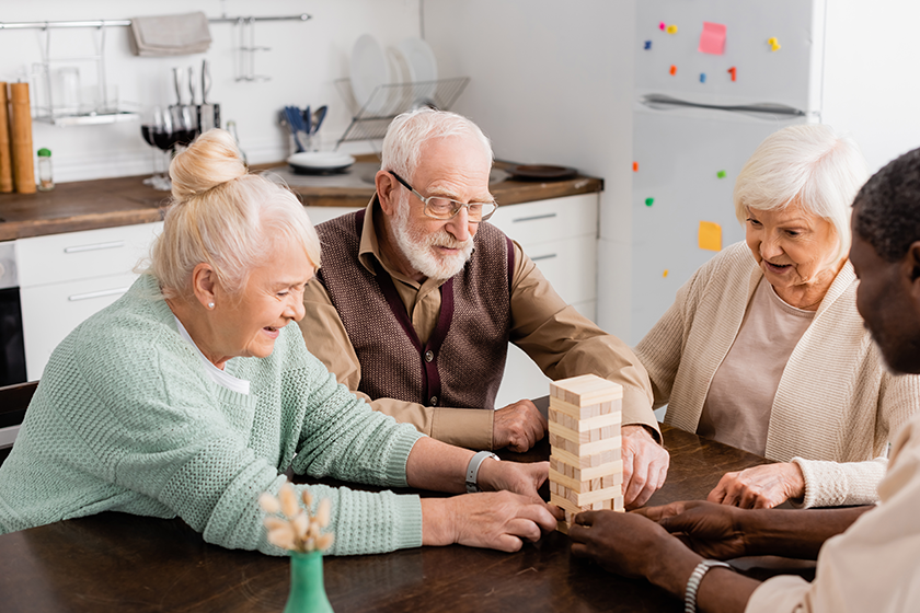 cheerful interracial pensioners smiling while playing tower wood blocks game