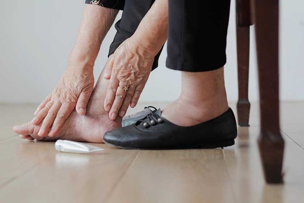 elderly woman putting cream swollen feet put shoes