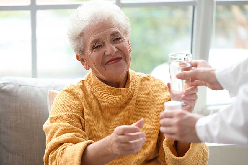 senior woman taking pills glass water doctor home