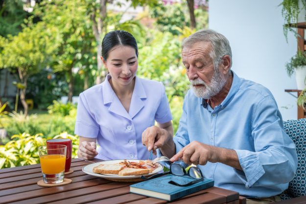 Nurse,Assist,Elderly,Senior,Man,To,Eat,Breakfast,At,Nursing