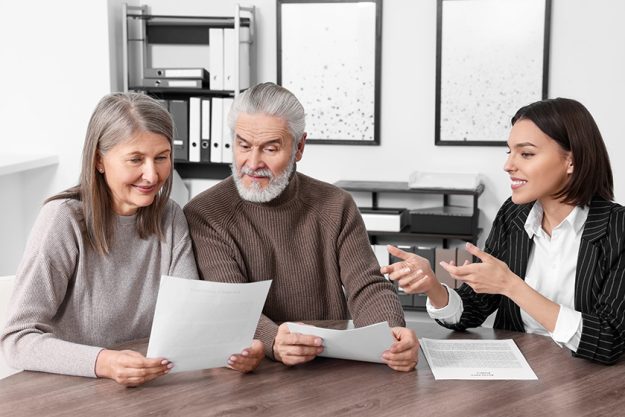 elderly couple consulting insurance agent pension plan wooden table indoors