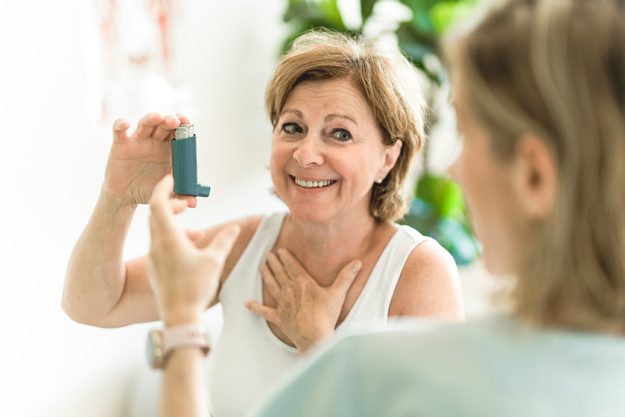 elderly woman using asthma inhaler clinic