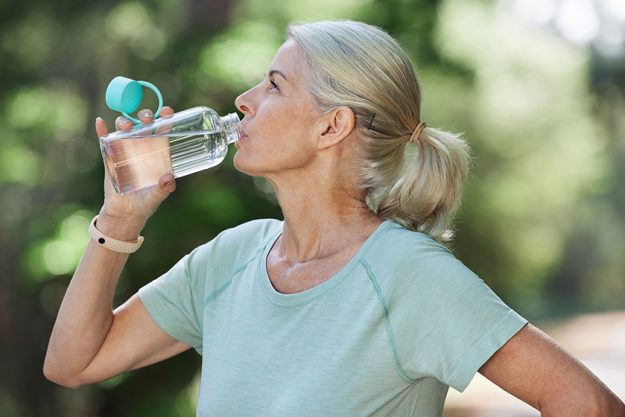 shot mature woman drinking water while exercising outdoors shot mature woman drinking water while exercising outdoors
