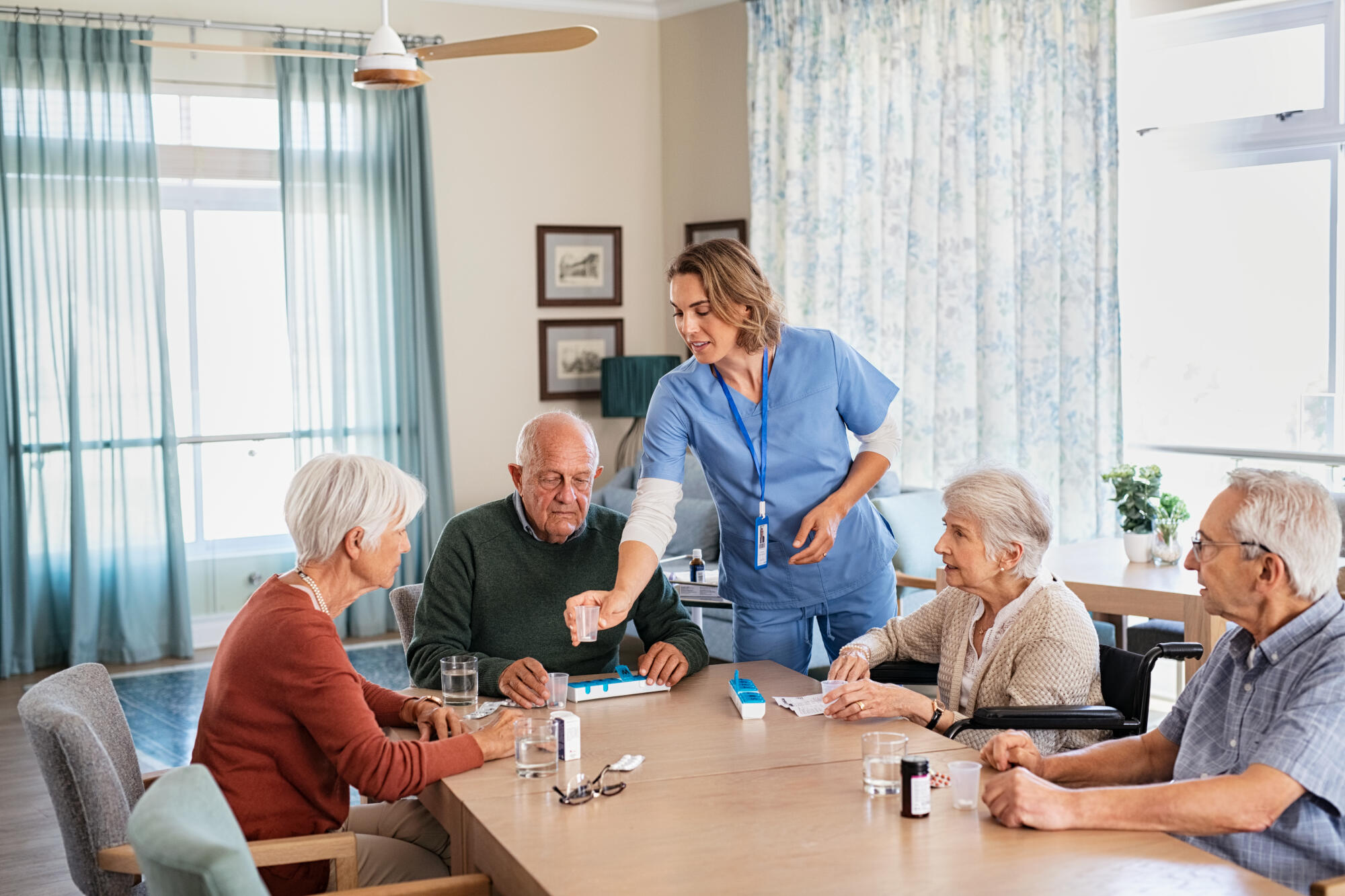Caregiver,Giving,Medicine,To,Group,Of,Senior,Men,And,Women