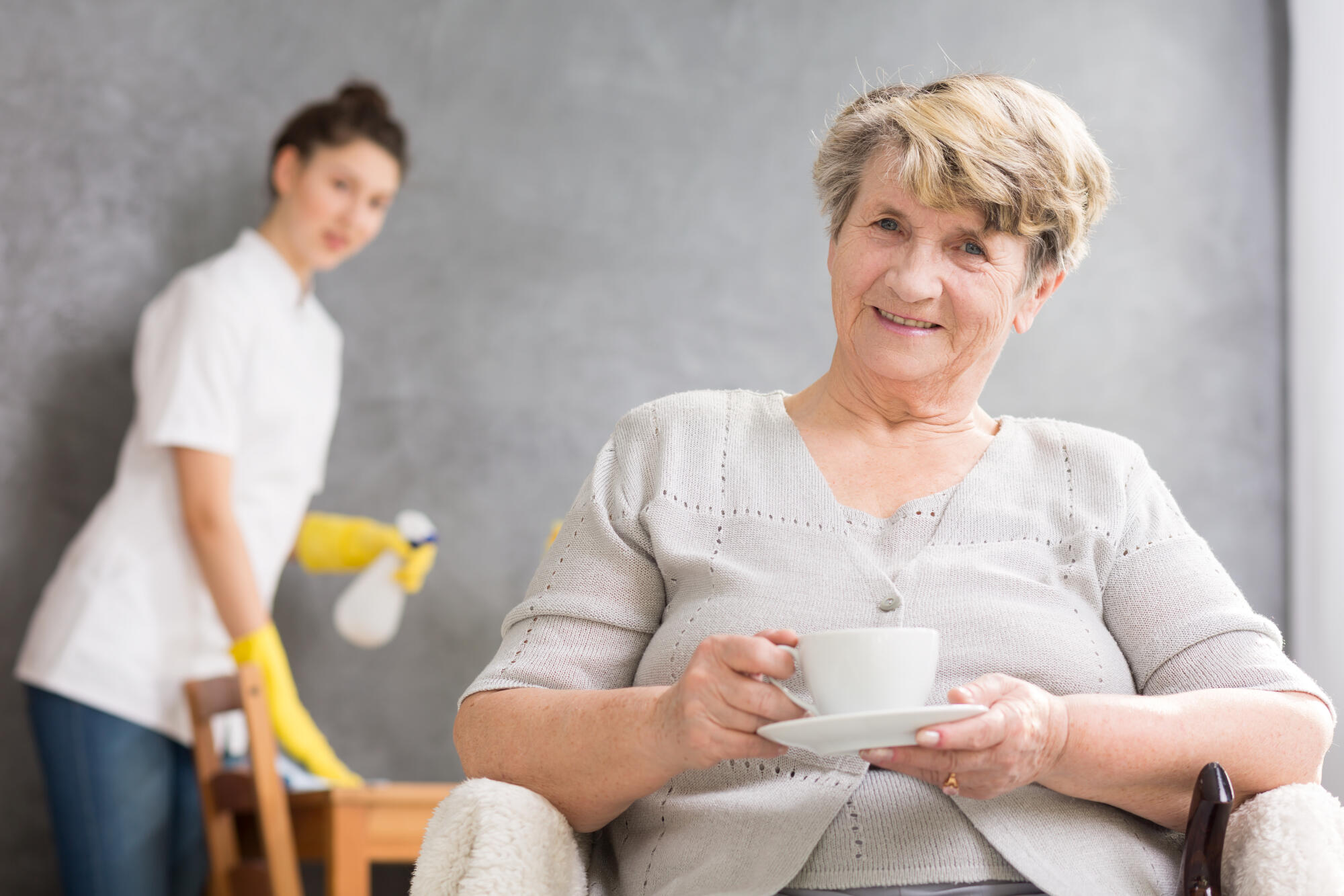 Servant,Help,Cleaning,The,Table,Behind,The,Senior,Woman,Sitting
