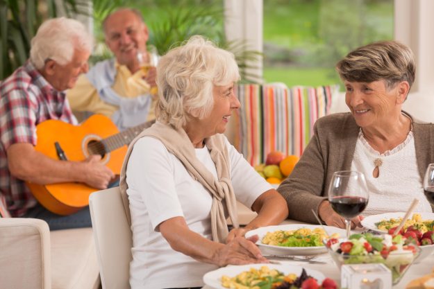 Two,Senior,Women,Talking,And,Drinking,Wine,,In,The,Background Two,Senior,Women,Talking,And,Drinking,Wine,,In,The,Background