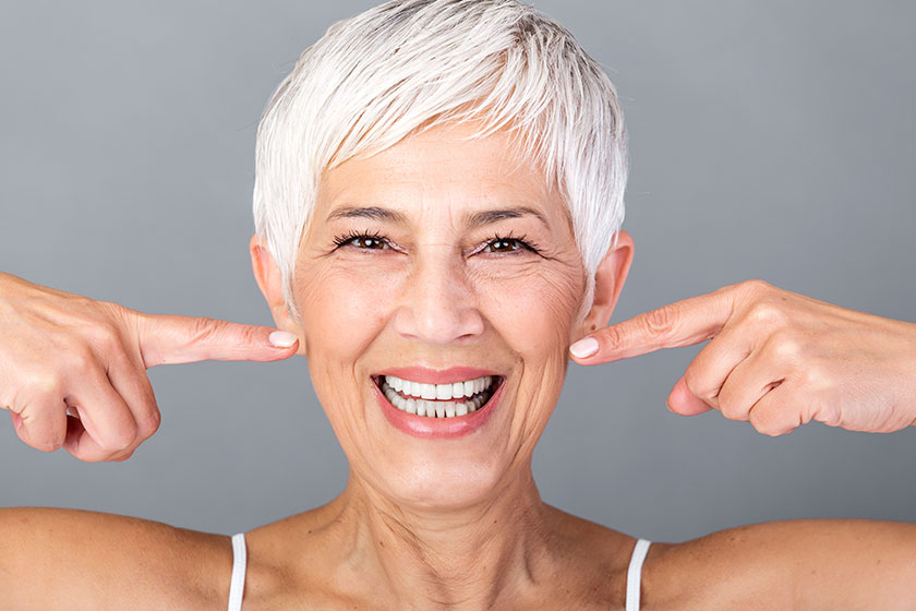 Beautiful caucasian smiling senior woman short grey hair pointing her