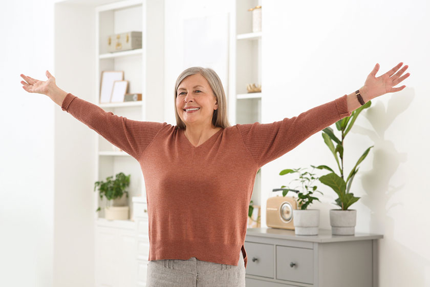 Beautiful senior woman raising hands room home Beautiful senior woman raising hands room home