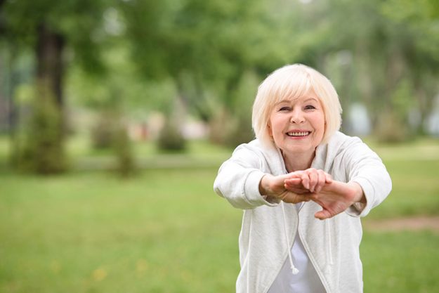 Elderly sportswoman exercising green lawn park Elderly sportswoman exercising green lawn park