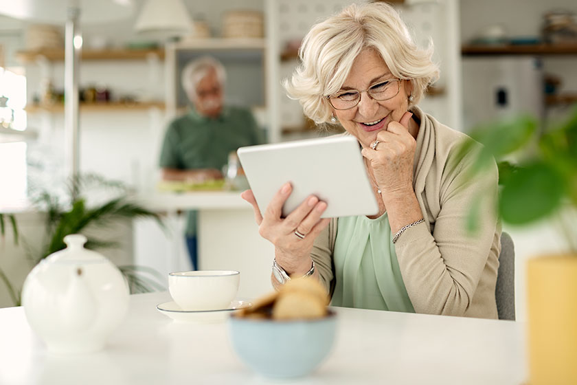 Happy senior woman using touchpad talking someone internet home Happy senior woman using touchpad talking someone internet home
