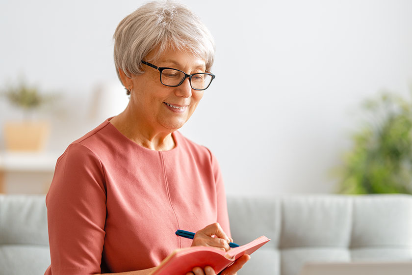 Joyful beautiful senior woman using laptop sitting sofa home