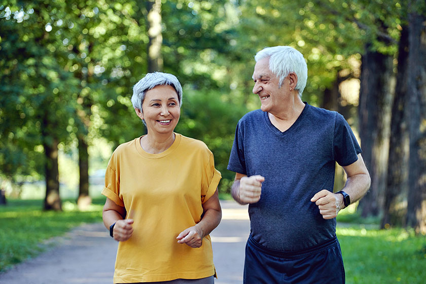 Mature smiling grey haired fit couple jogging summer park two Mature smiling grey haired fit couple jogging summer park two