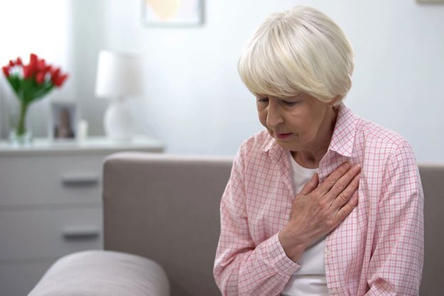 Old woman heart disease holding hand chest suffering tachycardia Old woman heart disease holding hand chest suffering tachycardia