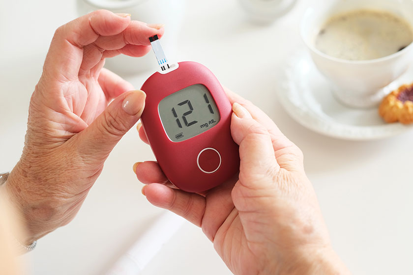 Older woman sitting next table examining her glucose level Older woman sitting next table examining her glucose level