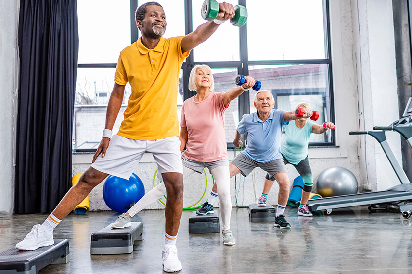 senior sportspeople synchronous exercising dumbbells step platforms gym