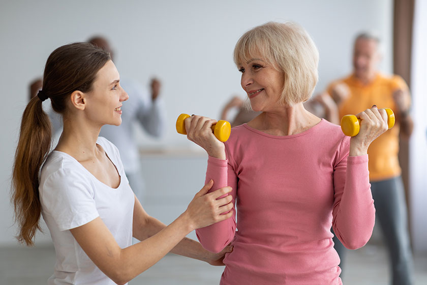 Fitness instructor assisting multiracial group of elderly people