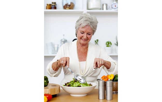 Happy senior woman cooking a salad