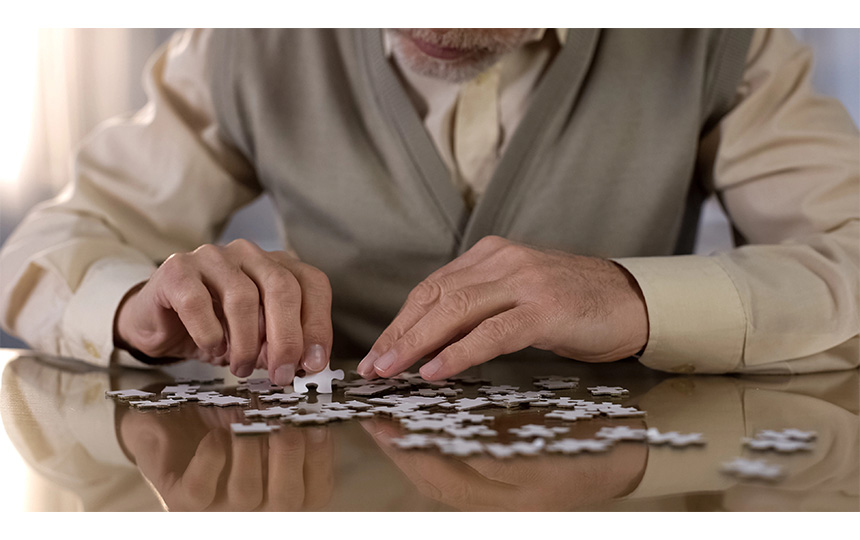 Senior man collecting puzzle alzheimer disease awareness concentration exercise