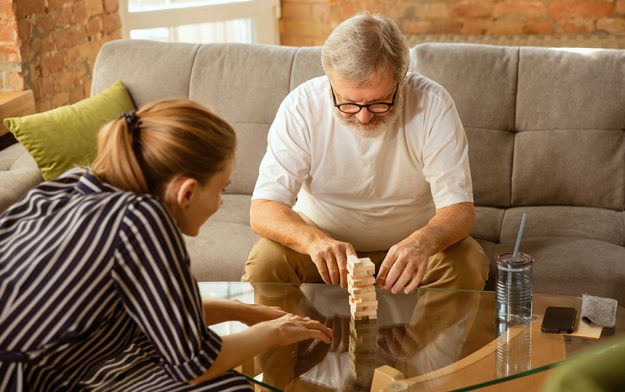 Senior man doing his wooden constructor at home concept of home studying