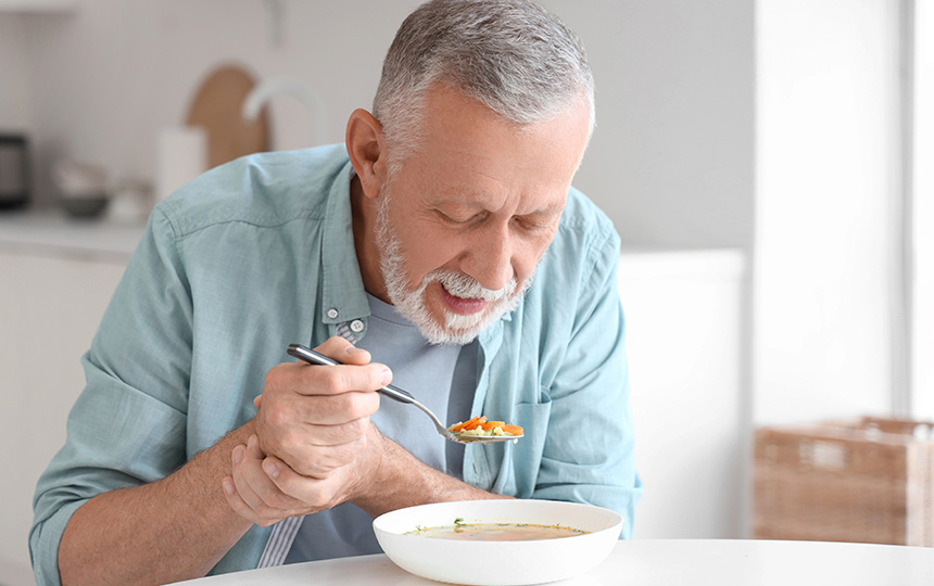 Senior man suffering parkinson syndrome eating table kitchen Senior man suffering parkinson syndrome eating table kitchen