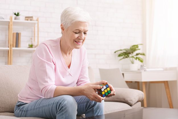Senior woman playing with rubiks cube during quarantine Senior woman playing with rubiks cube during quarantine