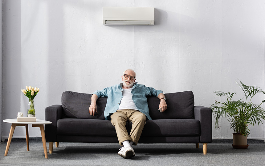 Smiling elderly man looking camera holding remote controller air conditioner Smiling elderly man looking camera holding remote controller air conditioner