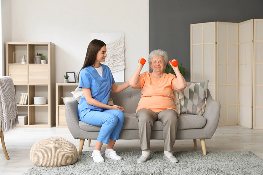 Young nurse senior woman dumbbells training home