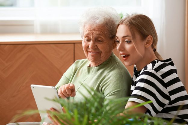 Young woman her grandmother using tablet computer bedroom Young woman her grandmother using tablet computer bedroom