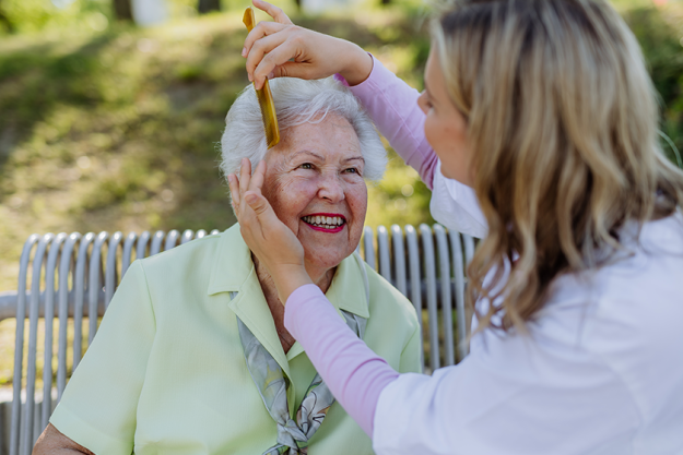 caregiver helping senior woman comb hair