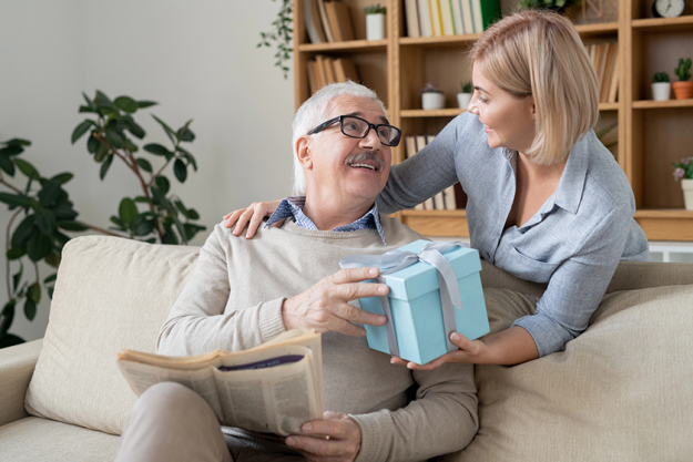 happy young casual woman giving her aged father packed birthday happy young casual woman giving her aged father packed birthday