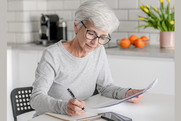 mature woman examines documents makes notes mature woman examines documents makes notes