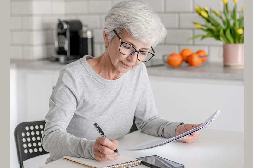 mature woman examines documents makes notes