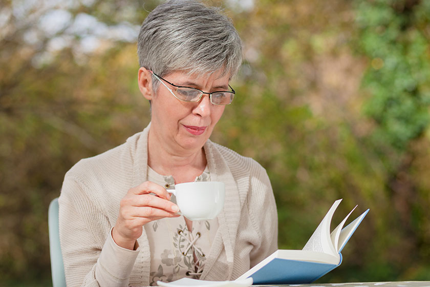 Older woman in the park reading a book