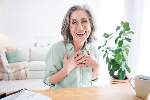 Portrait of cheerful excited person sit behind desk hands on chest laughing look camera hone Portrait of cheerful excited person sit behind desk hands on chest laughing look camera hone
