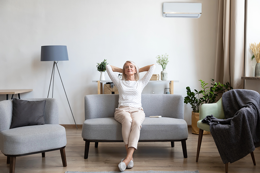 relaxed older woman sitting on couch in air conditioner