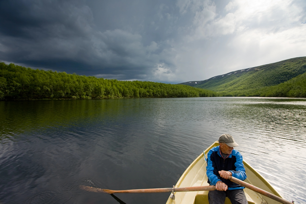 senior fisherman rowing in a boat