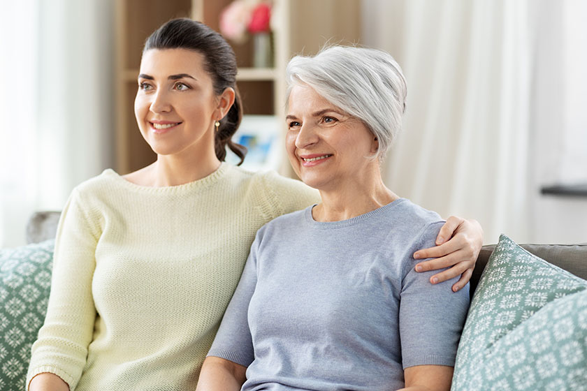 Senior mother with adult daughter hugging at home