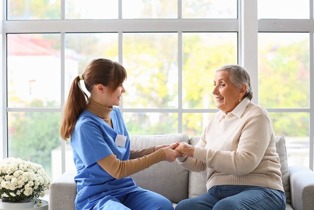 Senior woman caregiver holding hands home