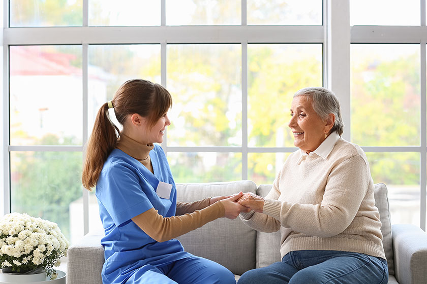 Senior woman caregiver holding hands home