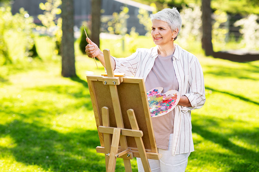 Senior woman with easel painting outdoors Senior woman with easel painting outdoors
