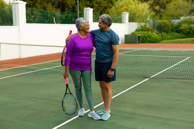 smiling biracial senior couple rackets