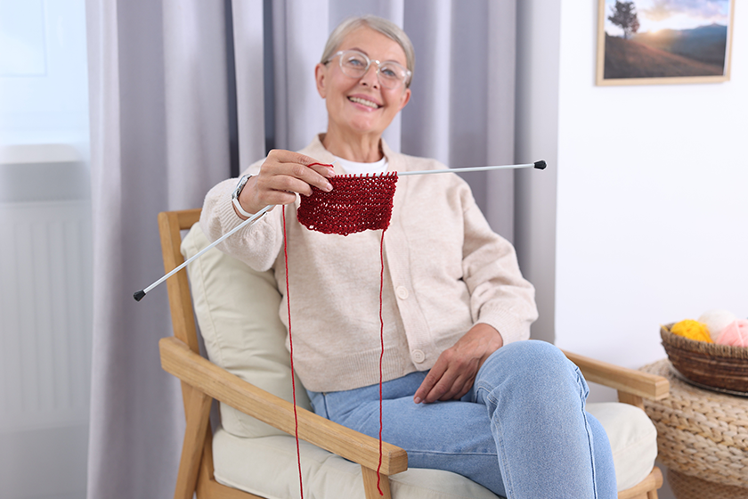 smiling senior woman showing knitting needles smiling senior woman showing knitting needles
