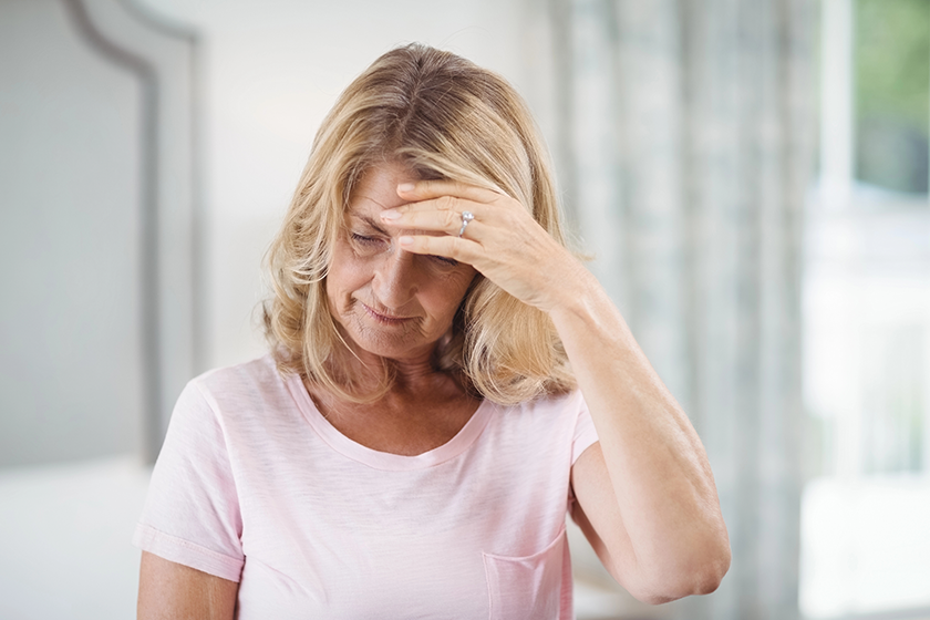 tense senior woman sitting in bedroom