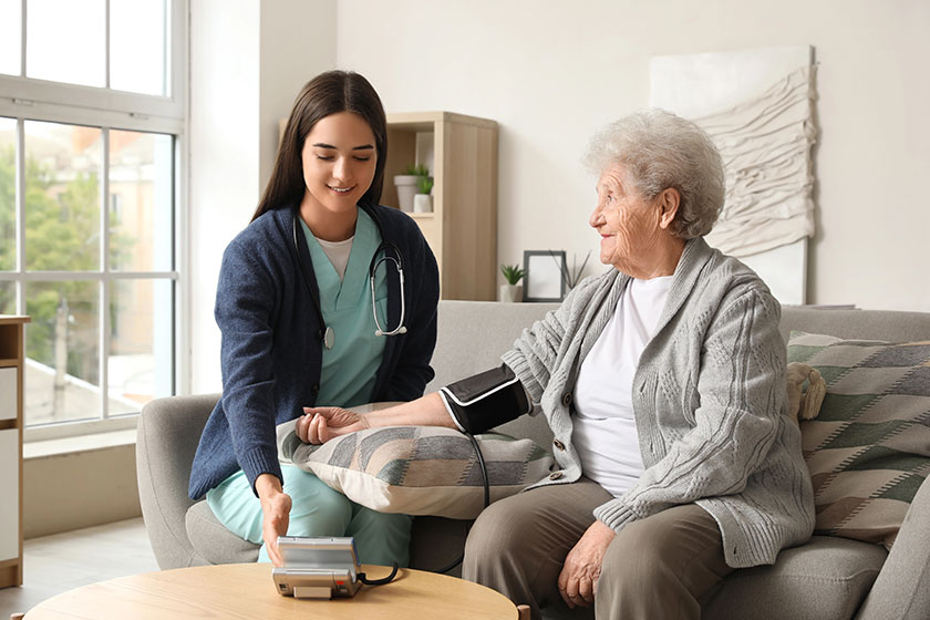 Young caregiver measuring blood pressure senior woman home Young caregiver measuring blood pressure senior woman home