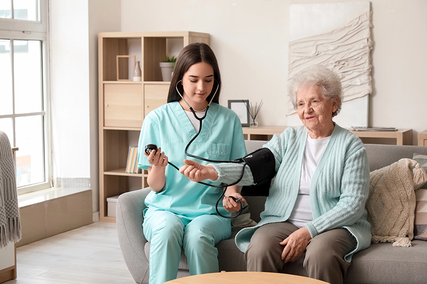 young caregiver measuring senior woman blood pressure